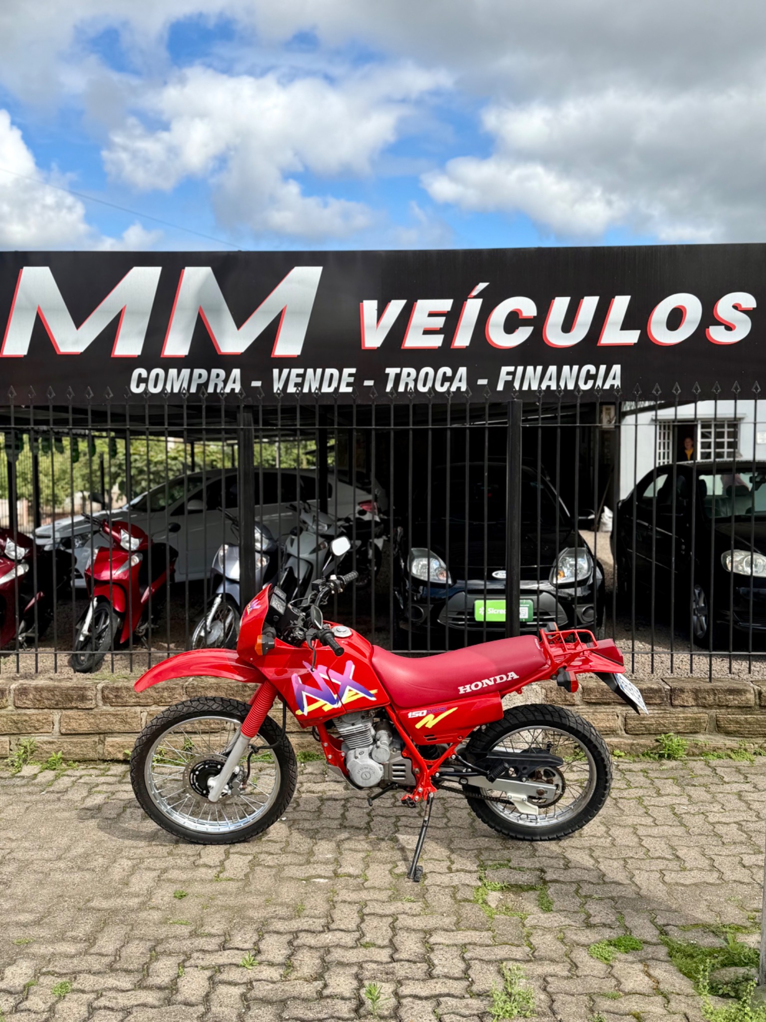 Honda NX 150 1992 vermelha diante da fachada da MM Veículos